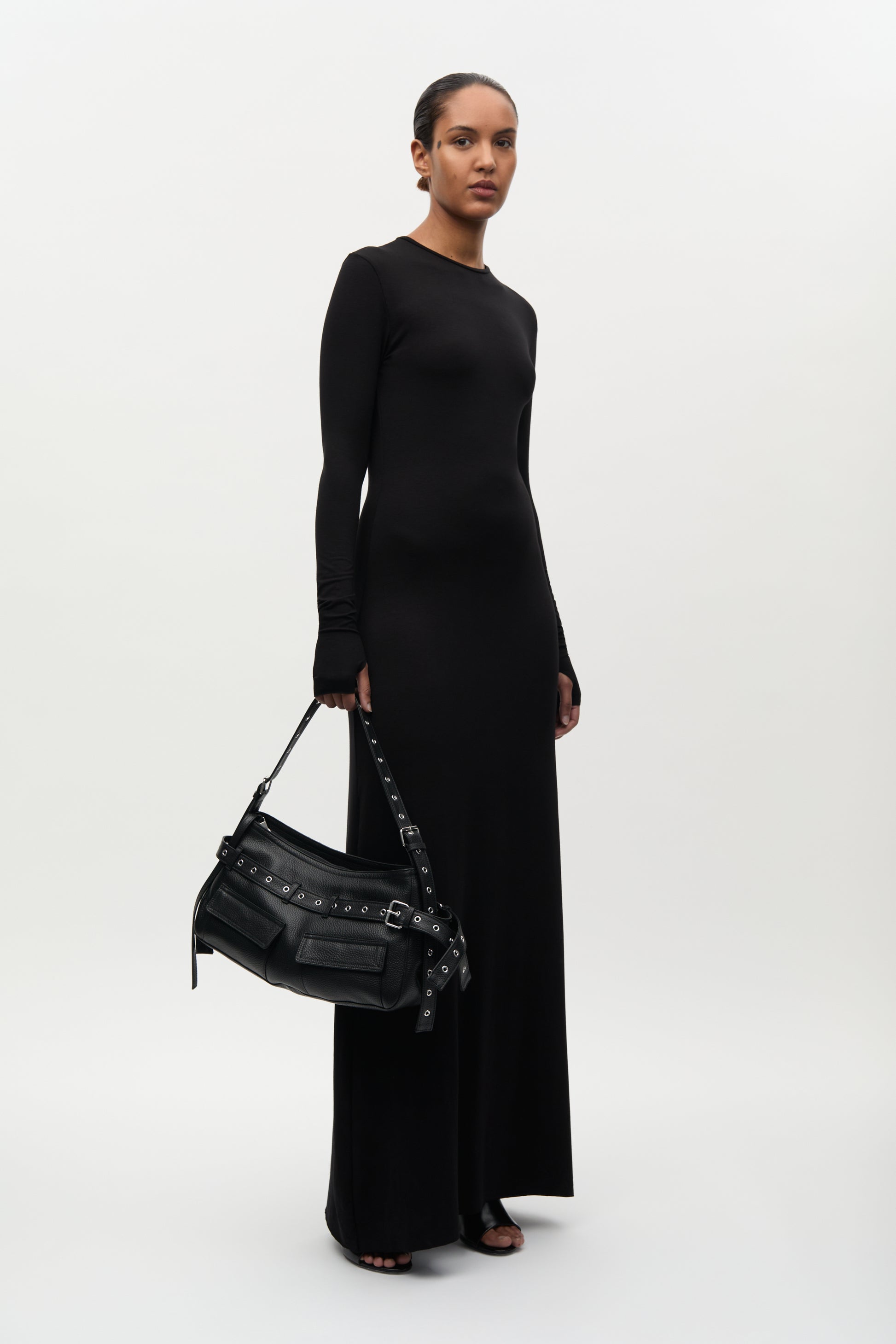 Woman holding a black handbag against a white background