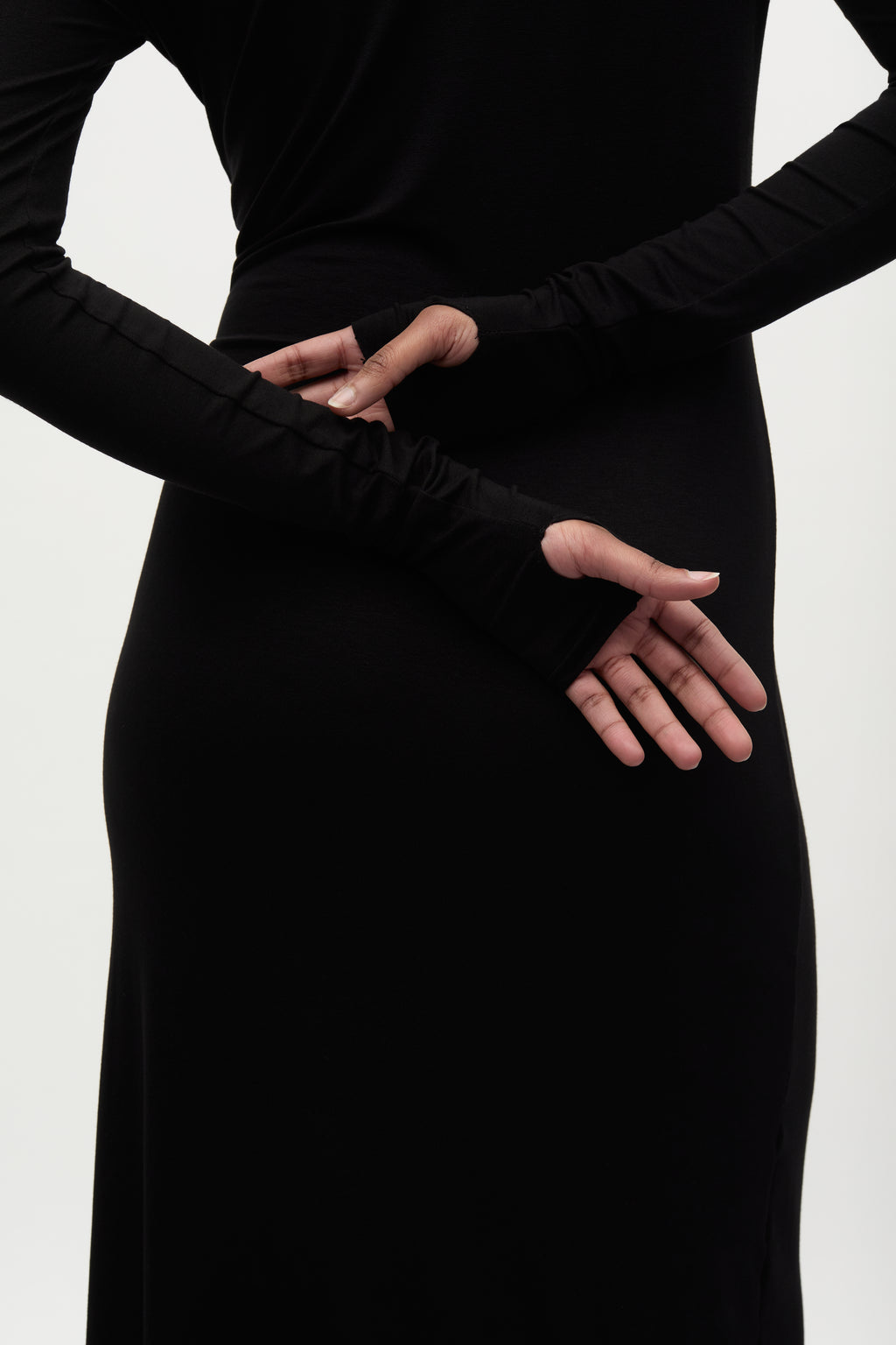 Person wearing a long black dress with long sleeves on a white background