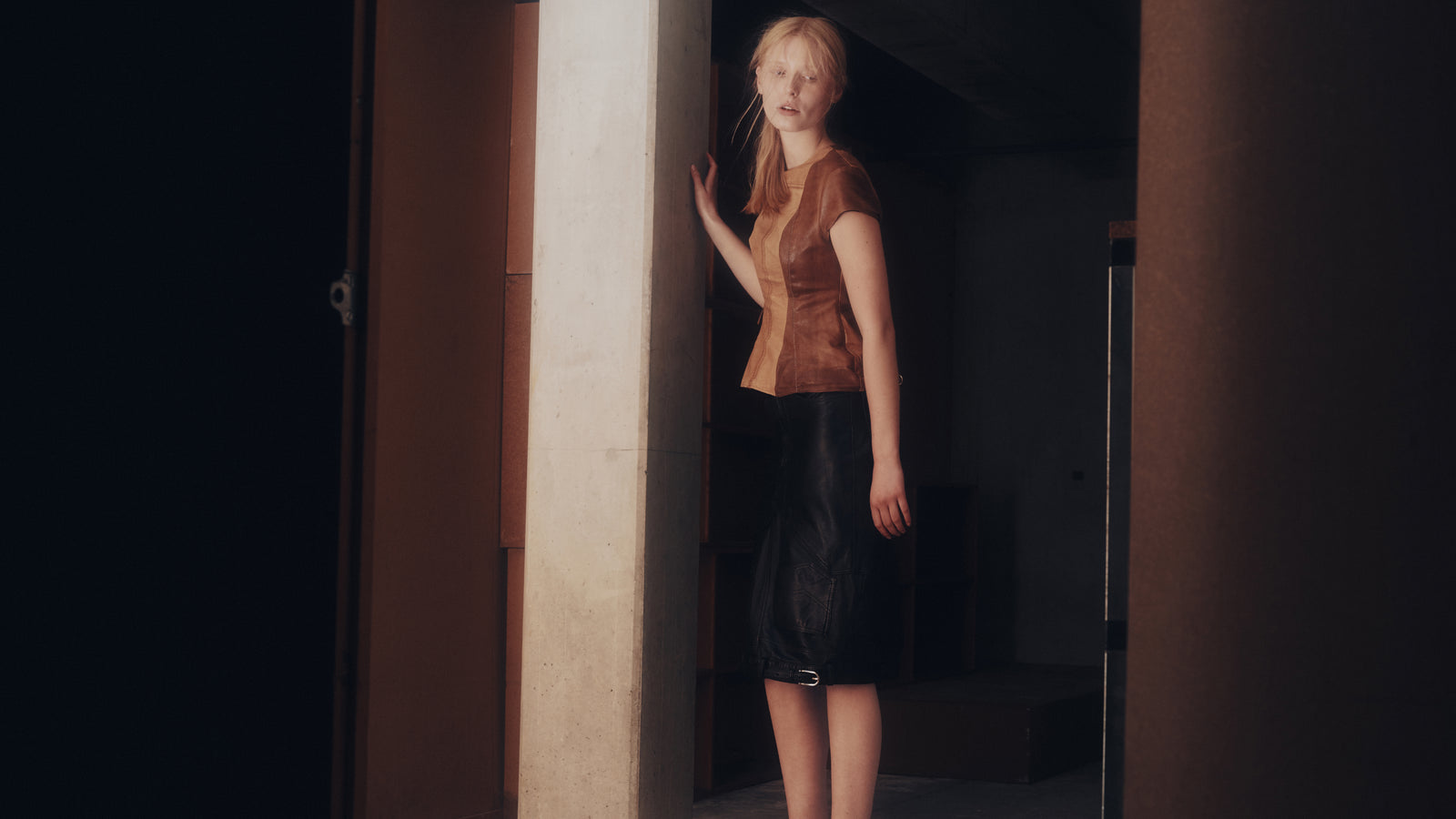 Taus Autumn Winter 2026, the Upcycled Leather Top in brown worn with a black leather pencil skirt