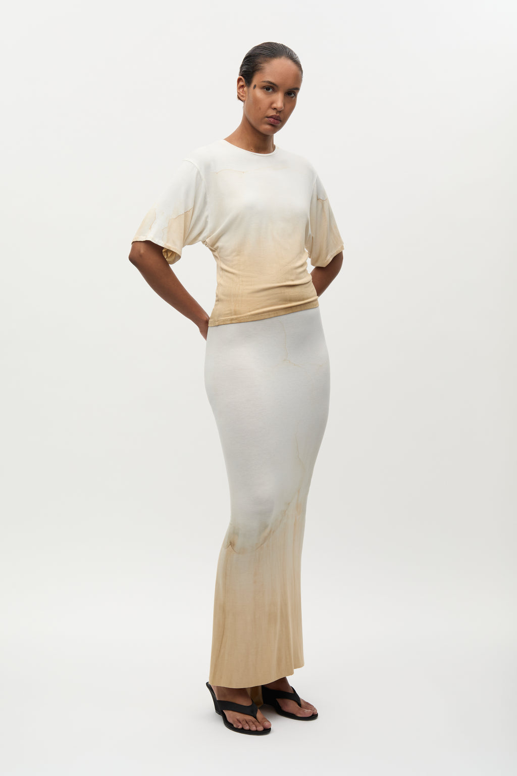Woman wearing a beige and white outfit on a white background
