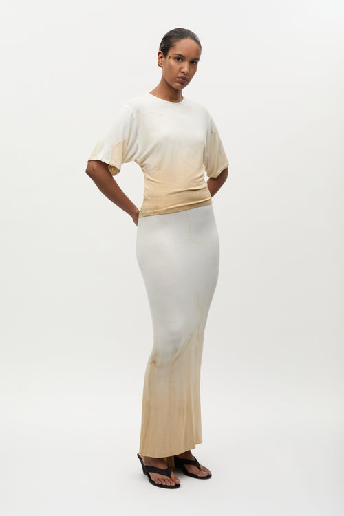 Woman wearing a beige and white outfit on a white background