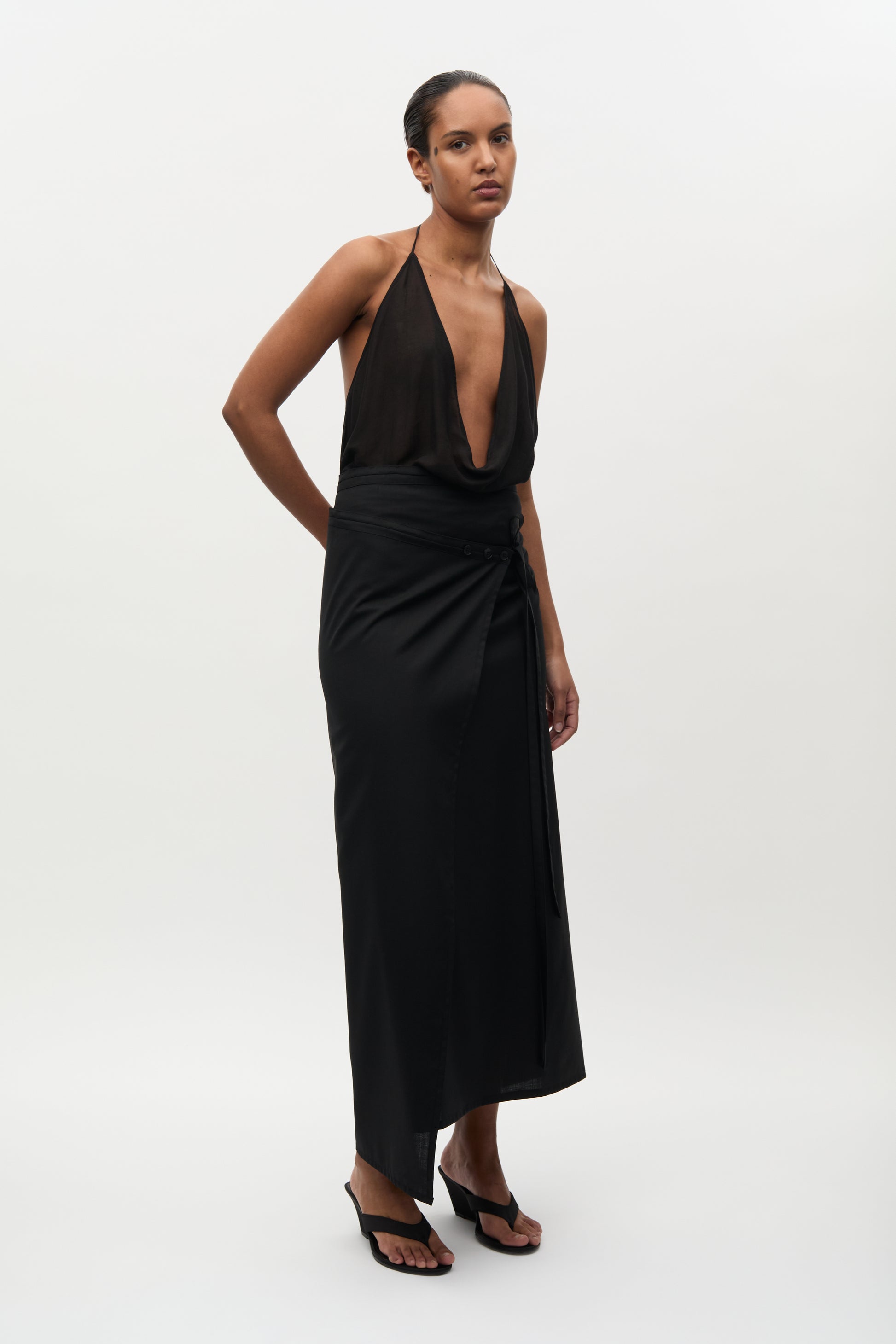 Woman wearing a black halter neck dress on a white background