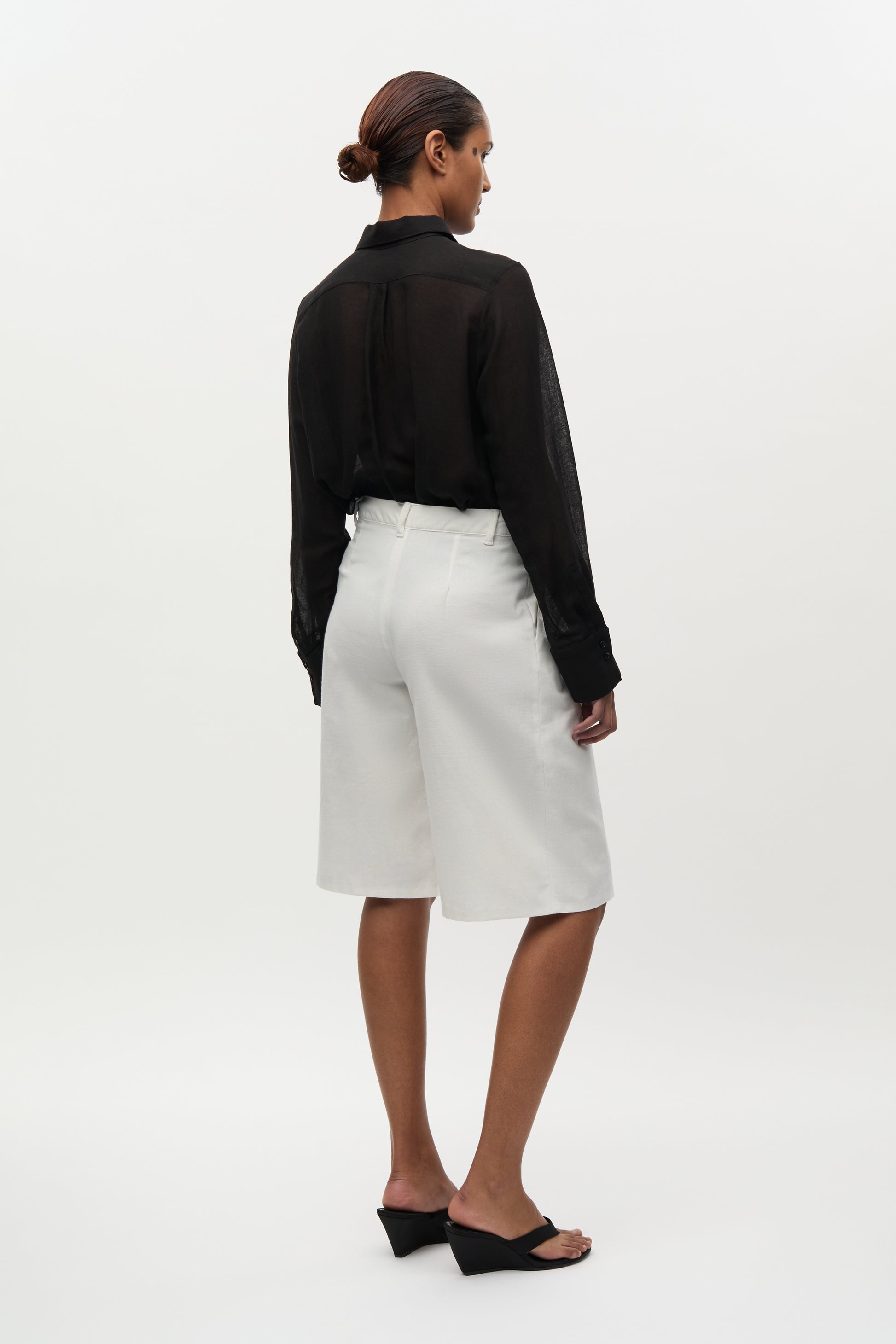 Woman wearing a black shirt and white shorts on a white background
