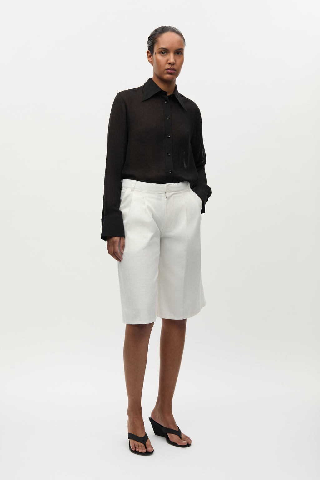 Woman wearing a black shirt and white shorts on a white background