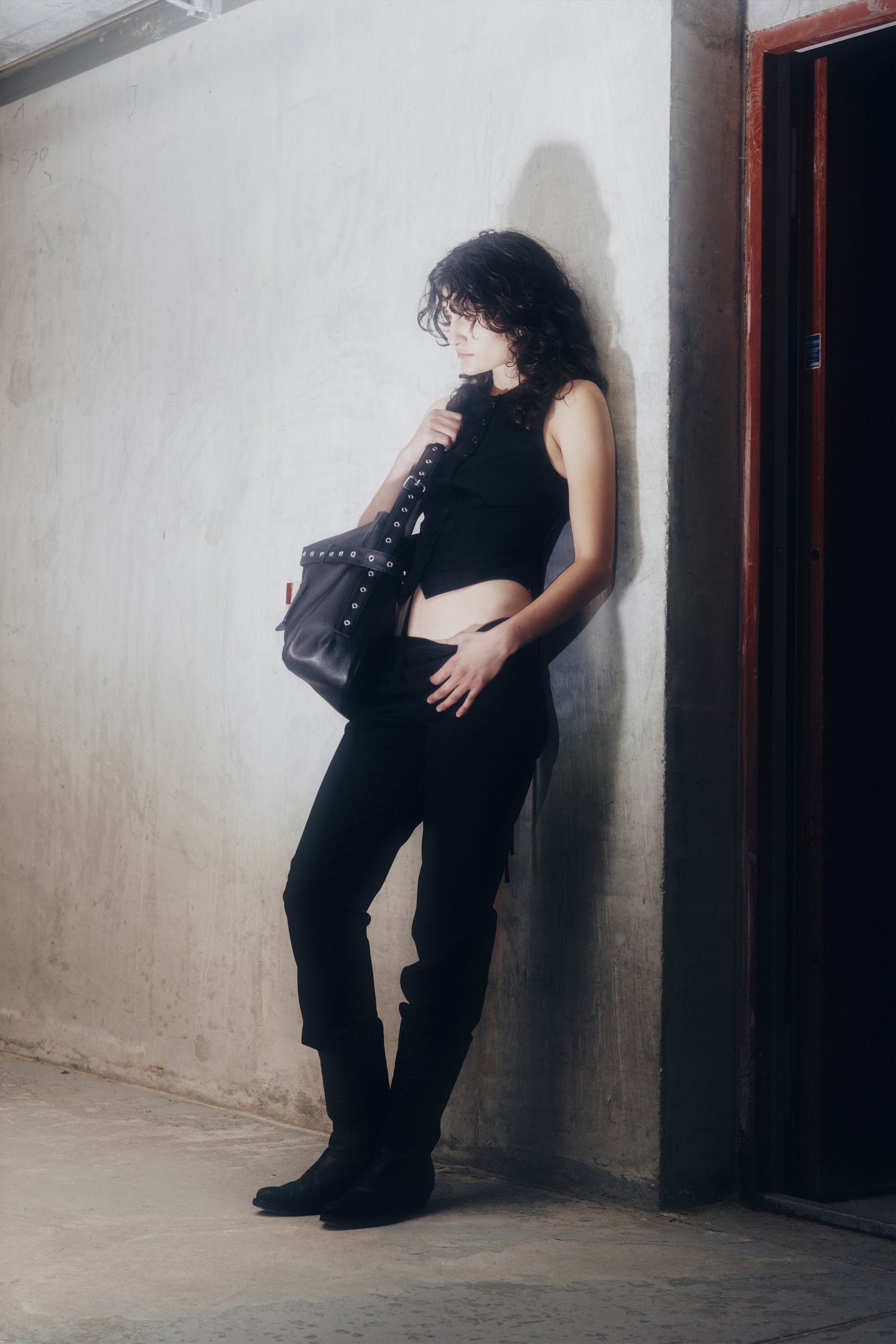 The Open-Back Waistcoat worn with black trousers, knee boots and the black leather Juho Bag