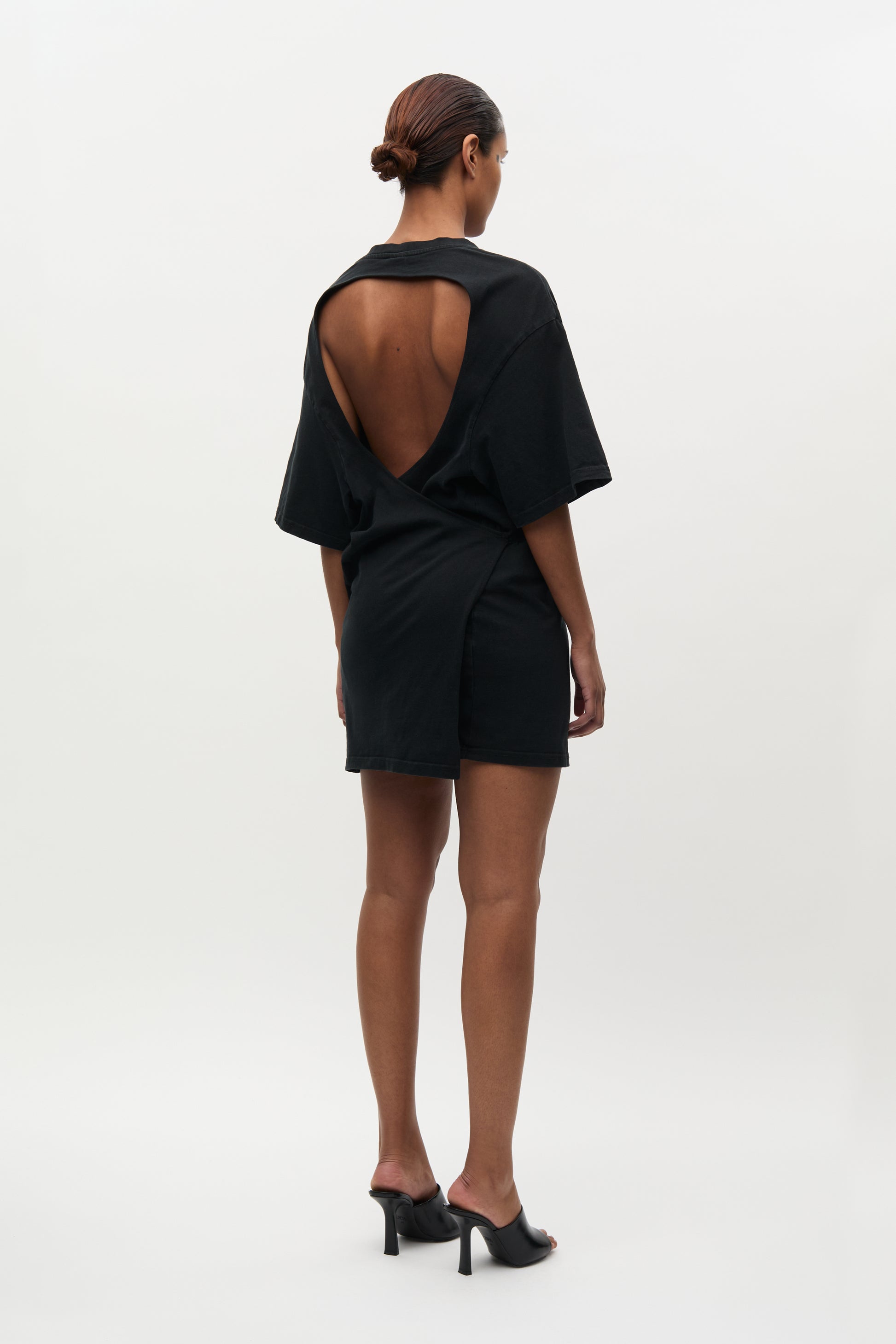 Person wearing a black outfit with open back on a white background