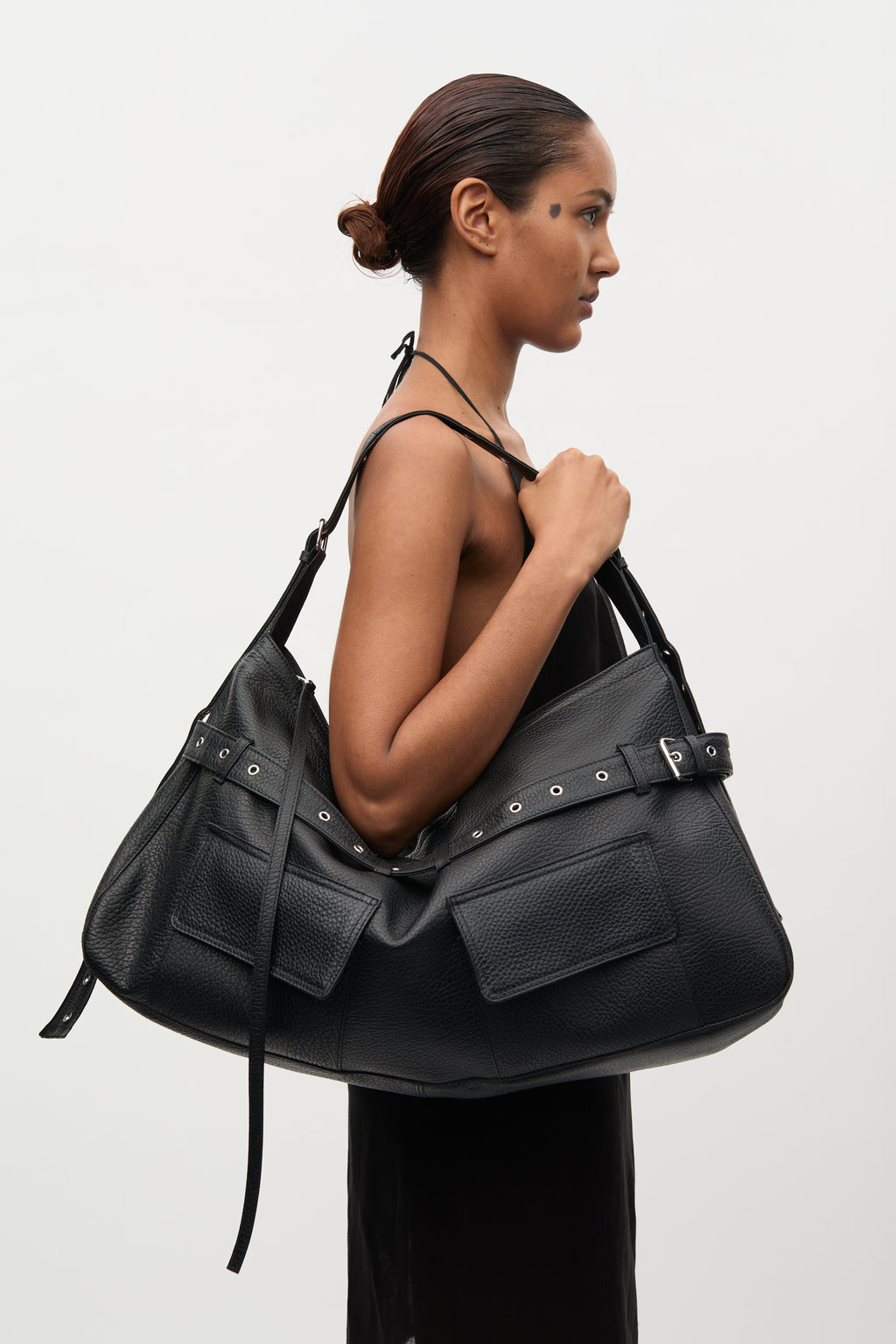 Woman holding a large black leather handbag against a white background