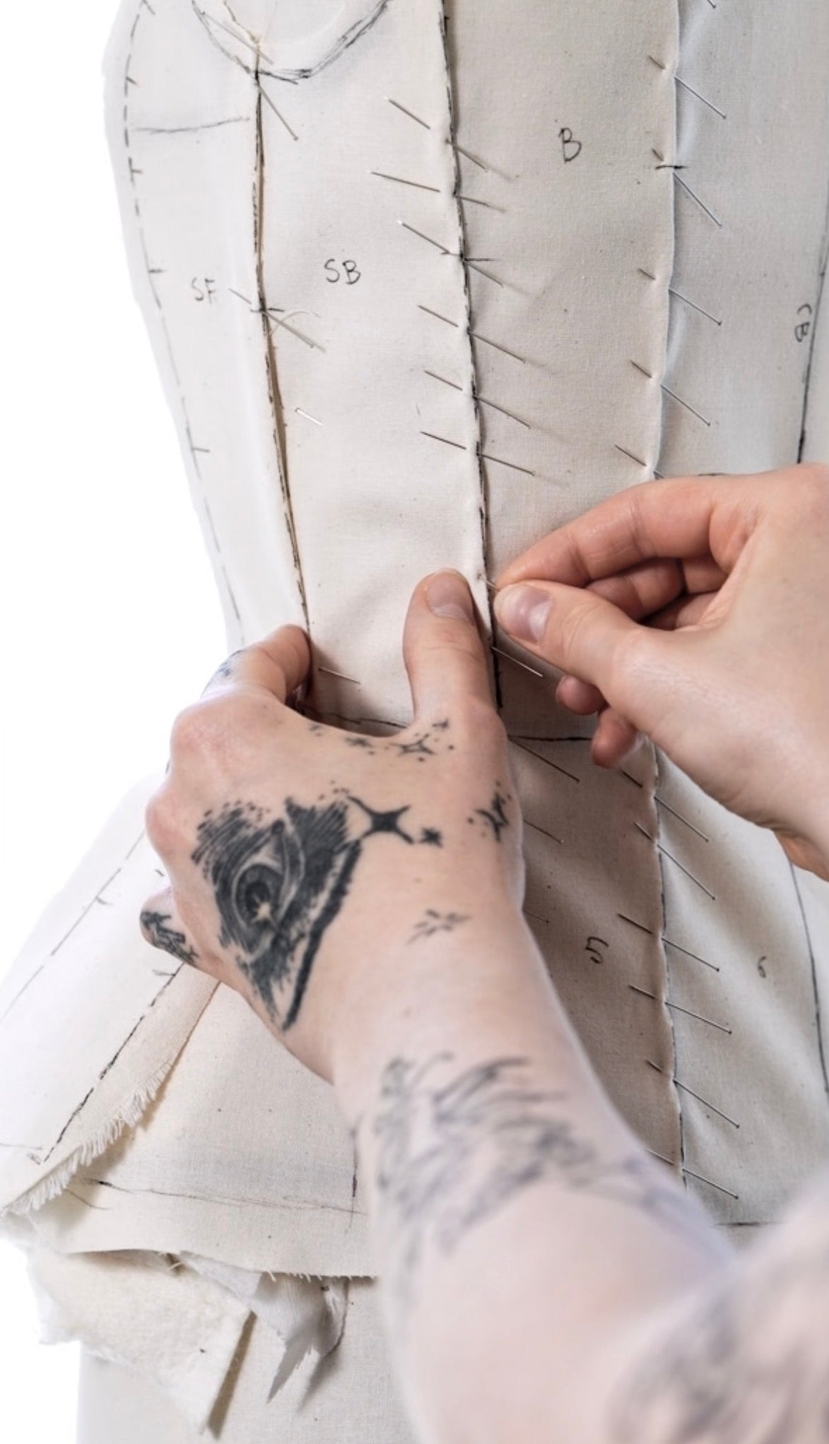 A toile being pinned and fitted by hand in the Taus studio