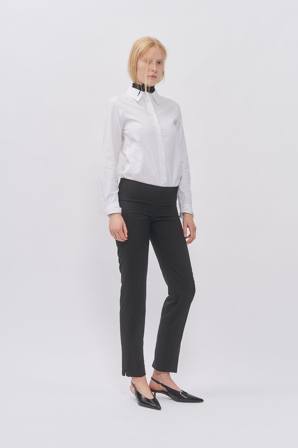 Taus Low-Waist Trousers in black with slim straight leg, styled with a white shirt and black slingback heels