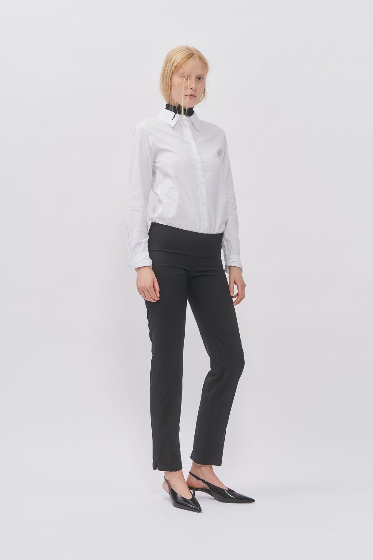 Taus Low-Waist Trousers in black with slim straight leg, styled with a white shirt and black slingback heels