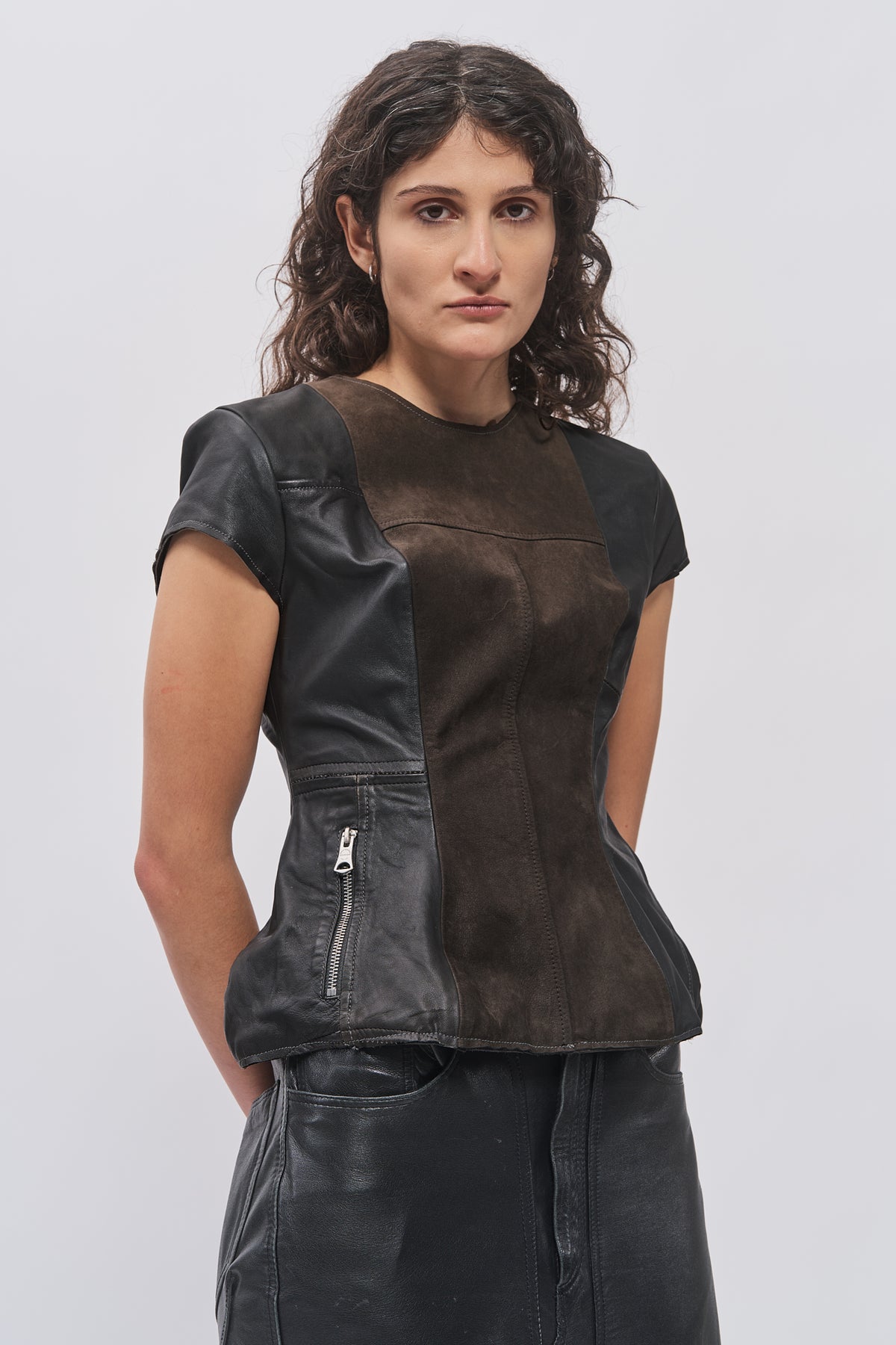 Close-up of Taus Upcycled Leather Top in black with contrast front panel and zip pocket