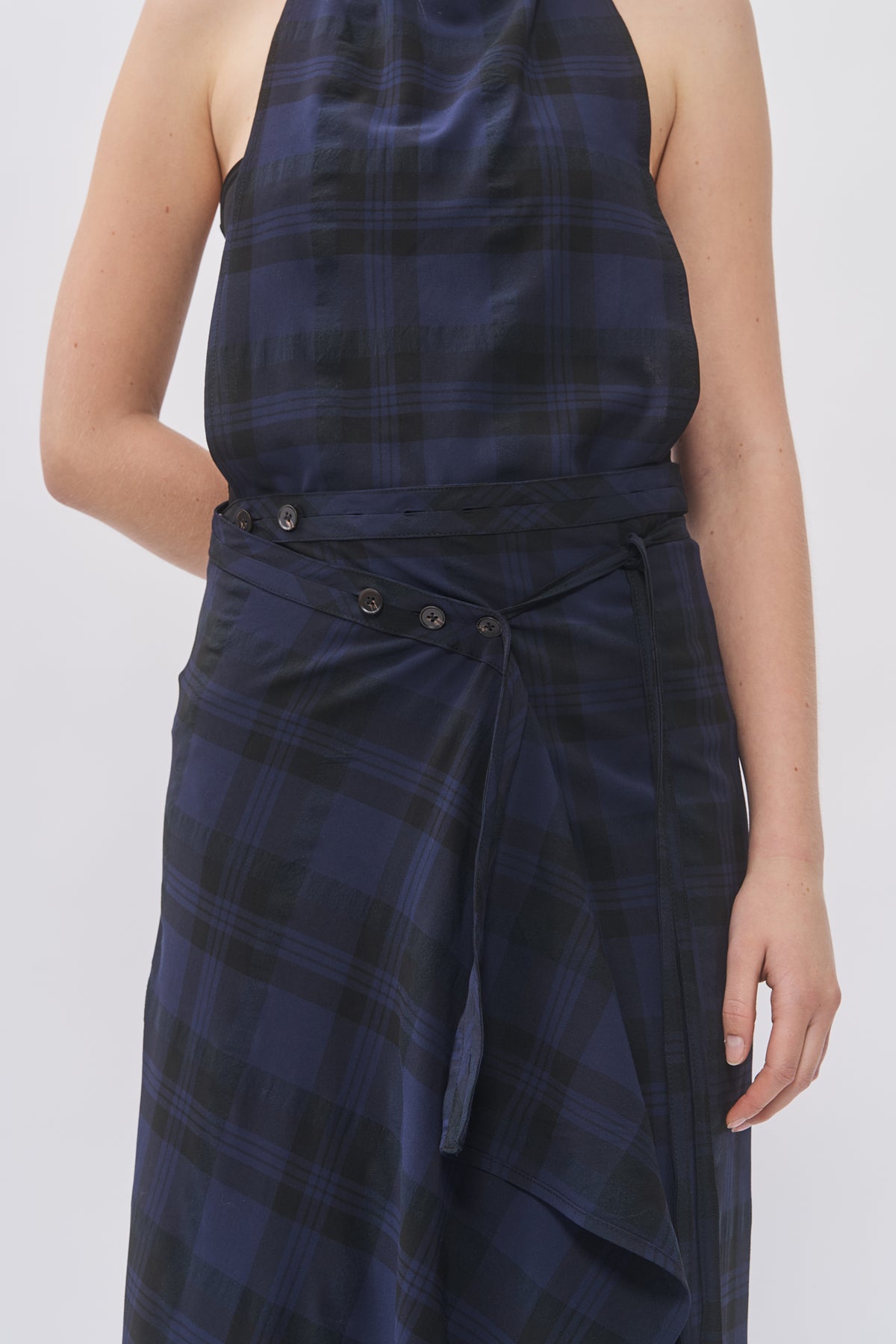 Close-up of Taus Wrap Skirt in navy and black check showing button waistband and draped wrap panel